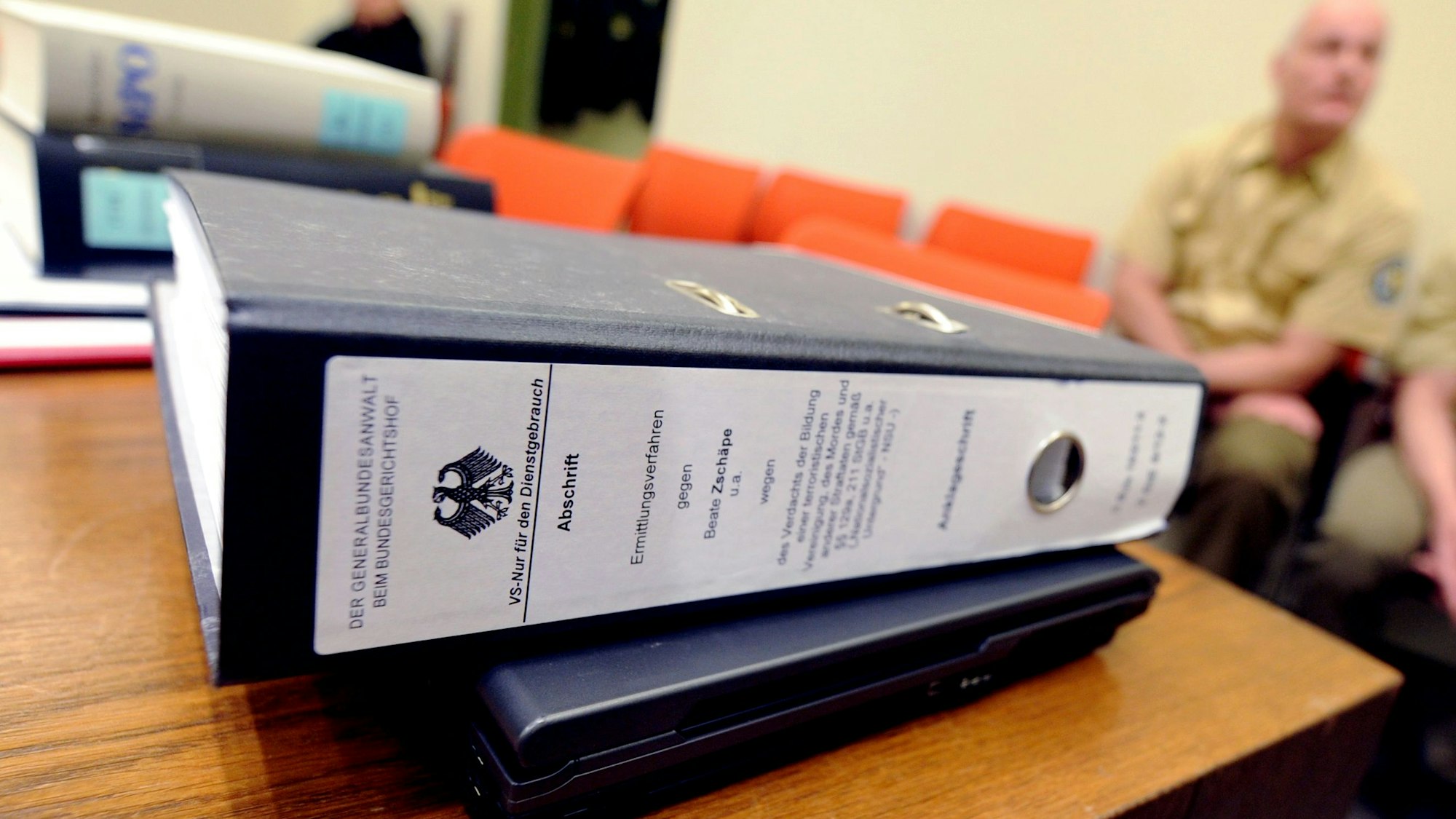 Eine Akte zum NSU-Prozess liegt im Gerichtssaal in München, (Bayern) während zwei Polizisten auf einer Bank sitzen. (Symbolbild)