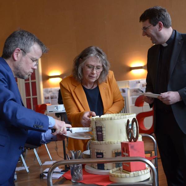 Die Vorstände Martin Jost (v.l.) und Maria Surges-Brilon schneiden die Geburtstagstorte an, Kreisdechant Guido Zimmermann assistiert.