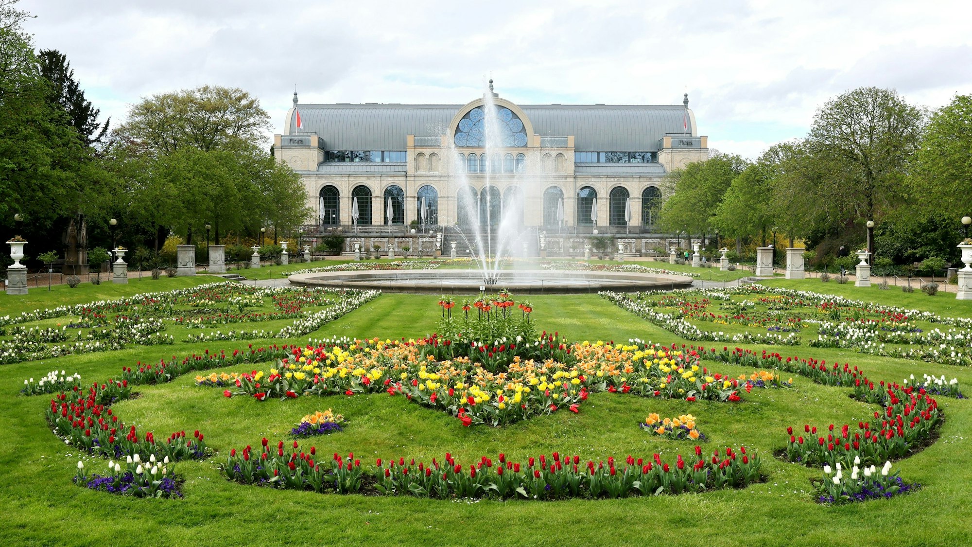 Die Flora in Köln, im Hintergrund der Glaspalast, der Springbrunnen sprudelt.