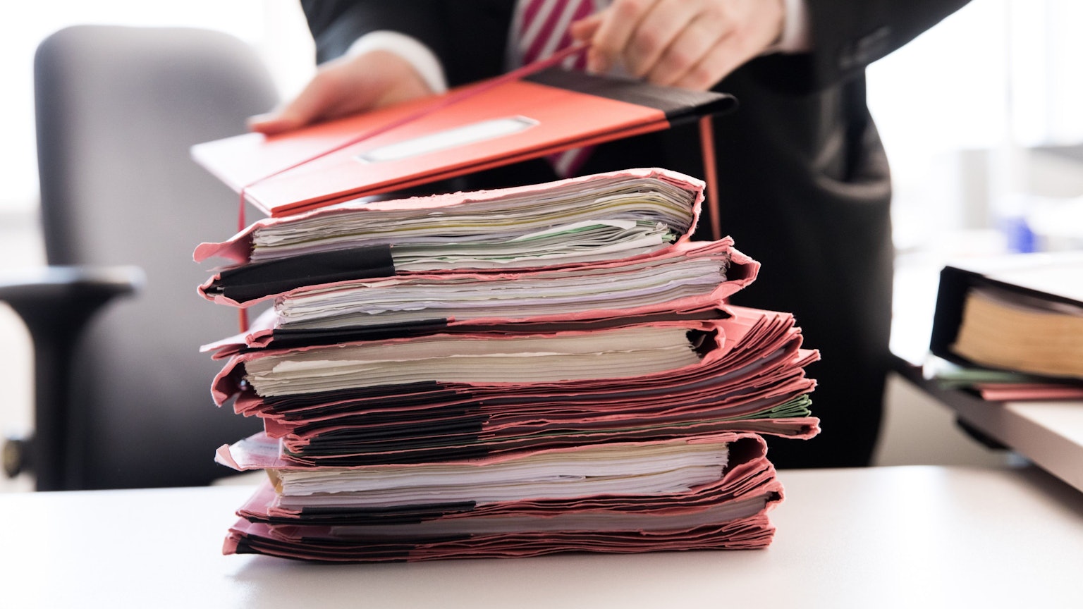 Ein Oberstaatsanwalt bindet einen Stapel Gerichtsakten (Symbolbild)