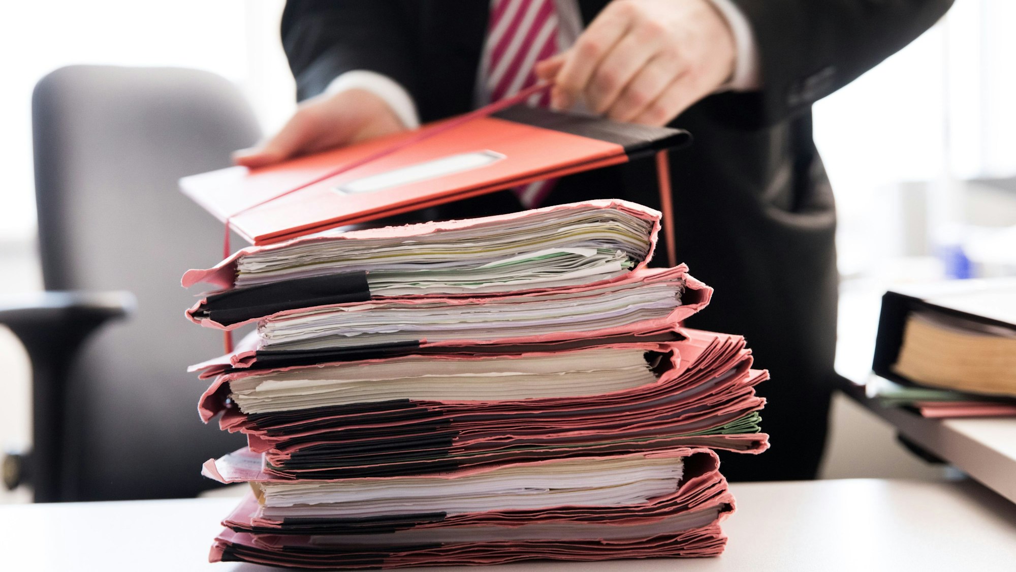 Ein Oberstaatsanwalt bindet einen Stapel Gerichtsakten (Symbolbild)