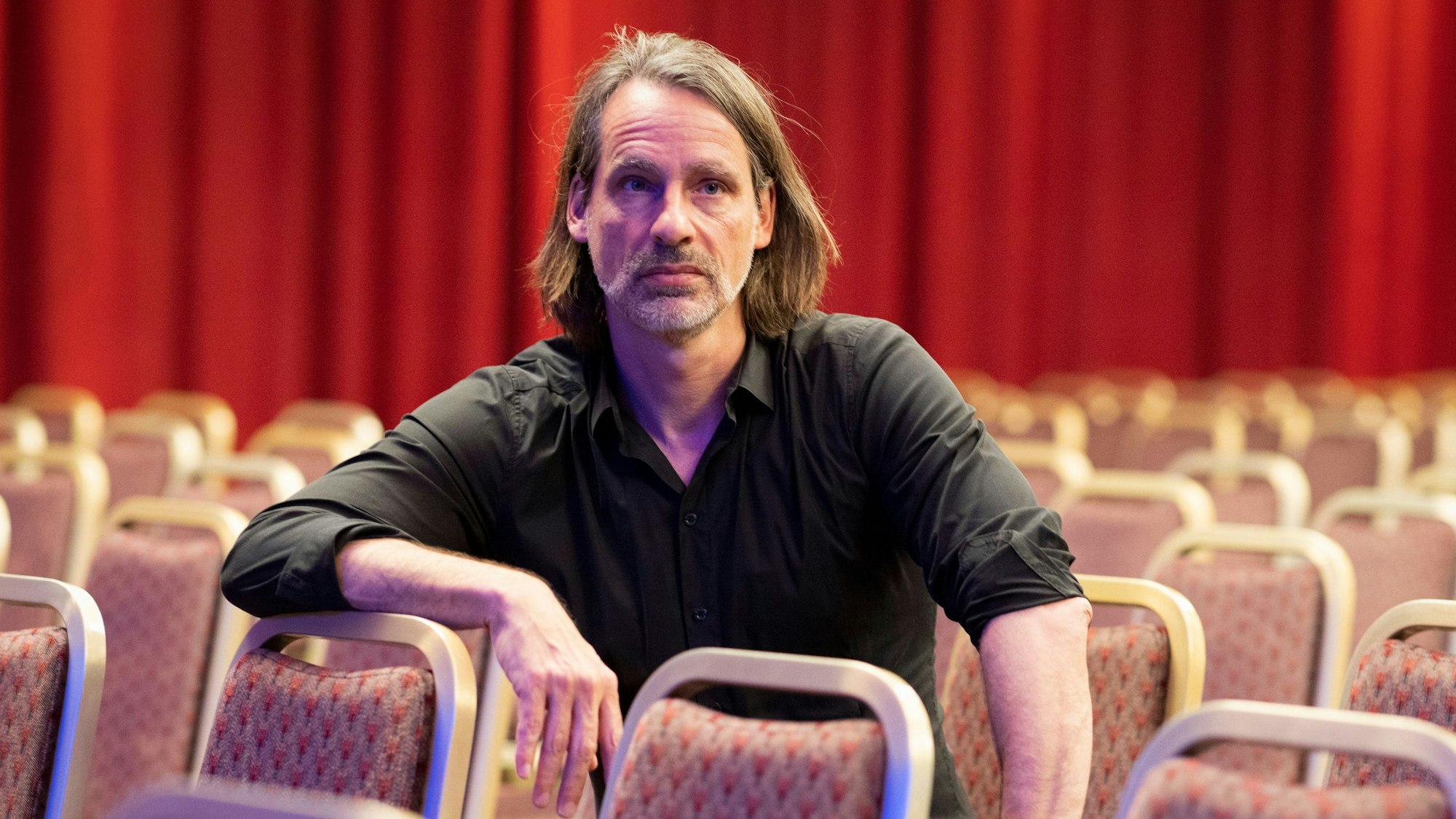 Philosoph Richard David Precht sitzt auf Stühlen in einem Raum.