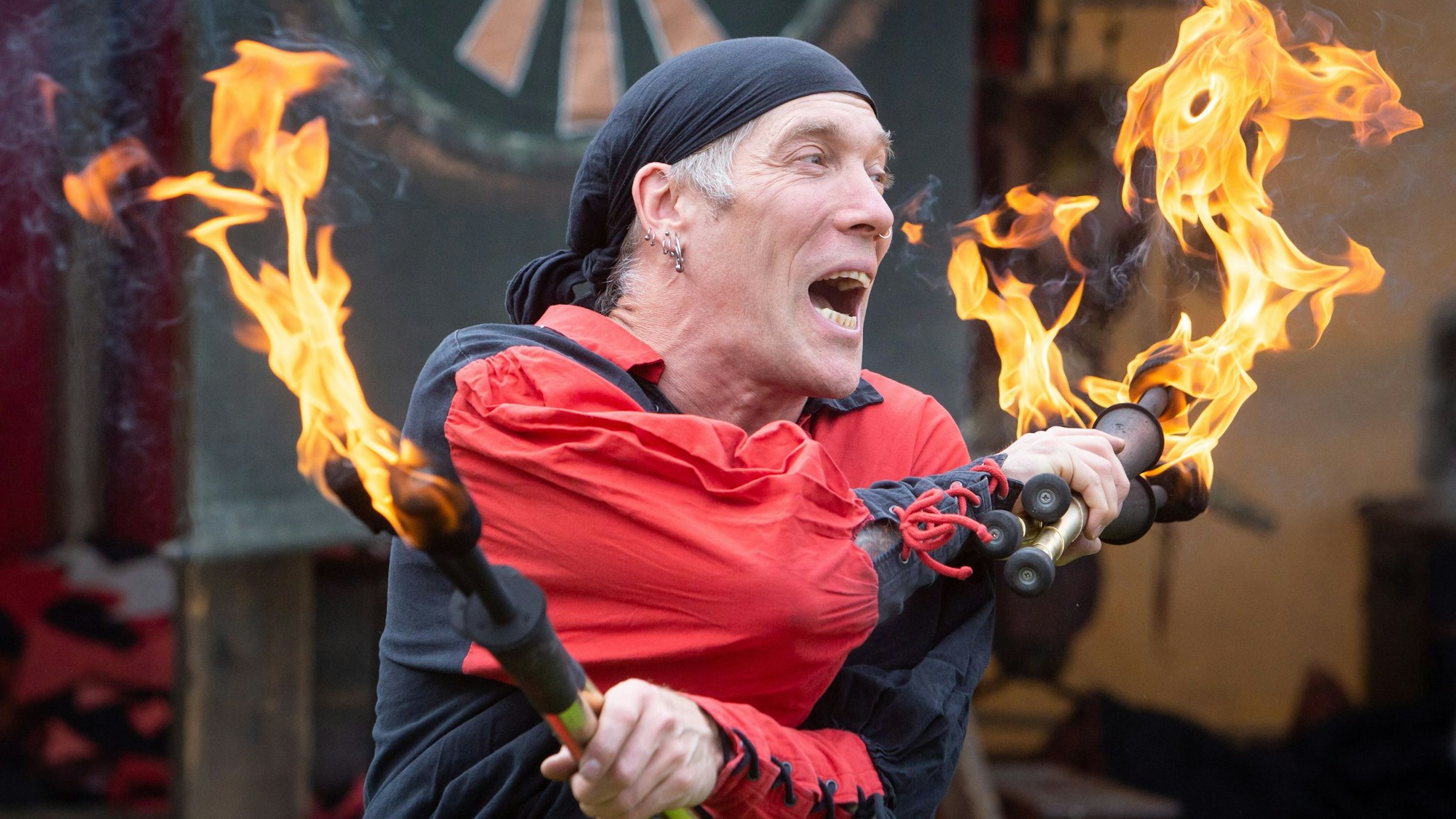 Ein Künstler jongliert mit zwei brennenden Fackeln.