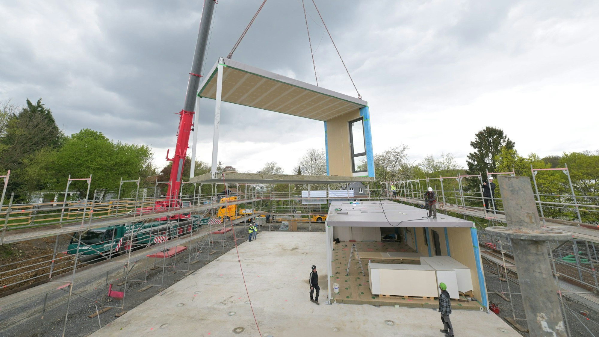 Ein Kran hebt ein Modul auf ein anderes.