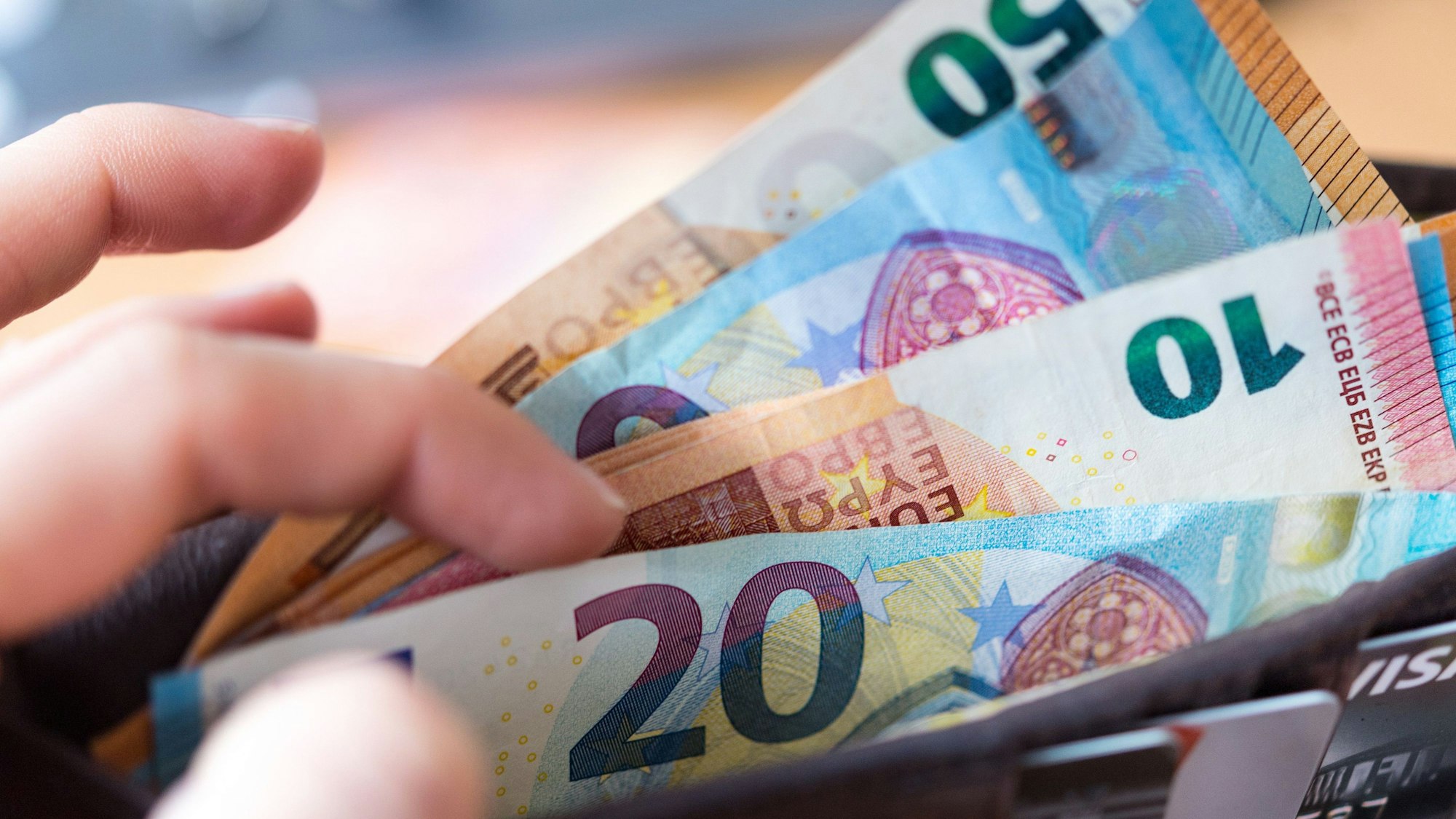 Eine Frau hält eine Geldbörse mit Banknoten in der Hand