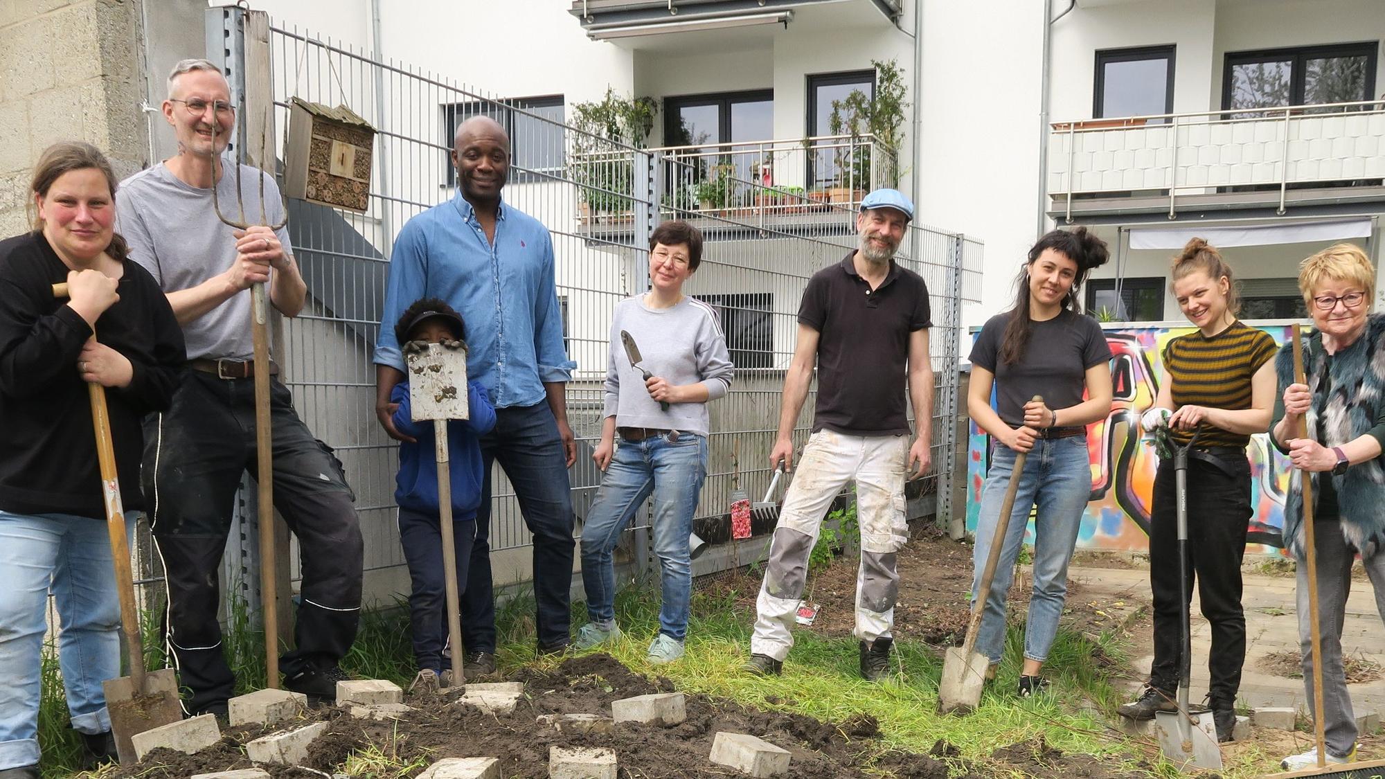 Teilnehmer mit Spaten vor umgegrabenem Erdreich
