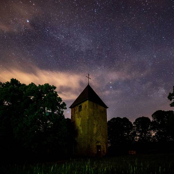 Der Wollseifener Kirchturm und einige Baumkronen ragen in den Sternenhimmel.