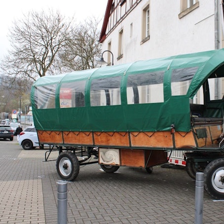 Ein Planwagen steht verkeilt an einer Hauswand.