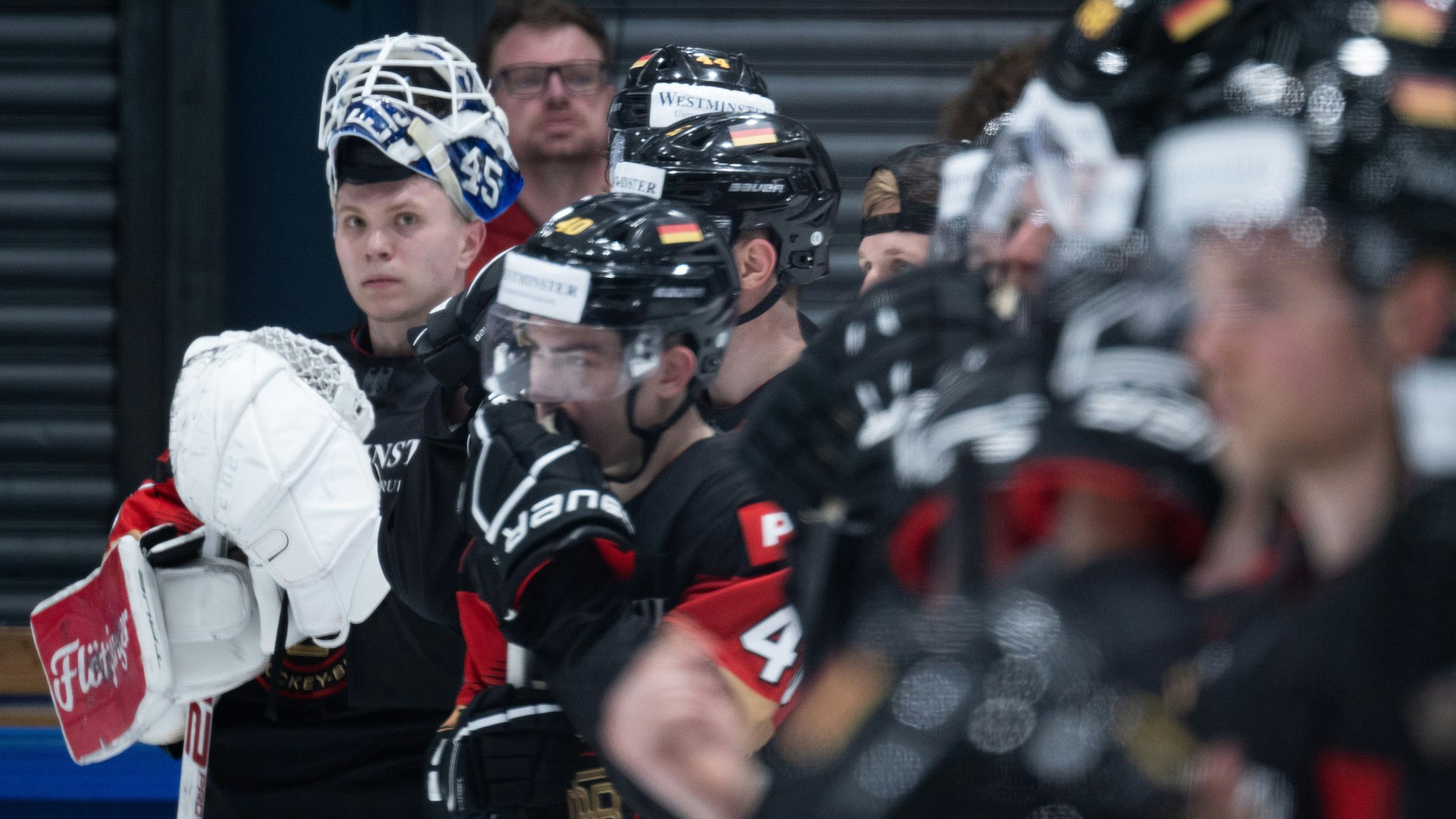 Eishockeyspieler stehen unscharf vor einem Torwart.
