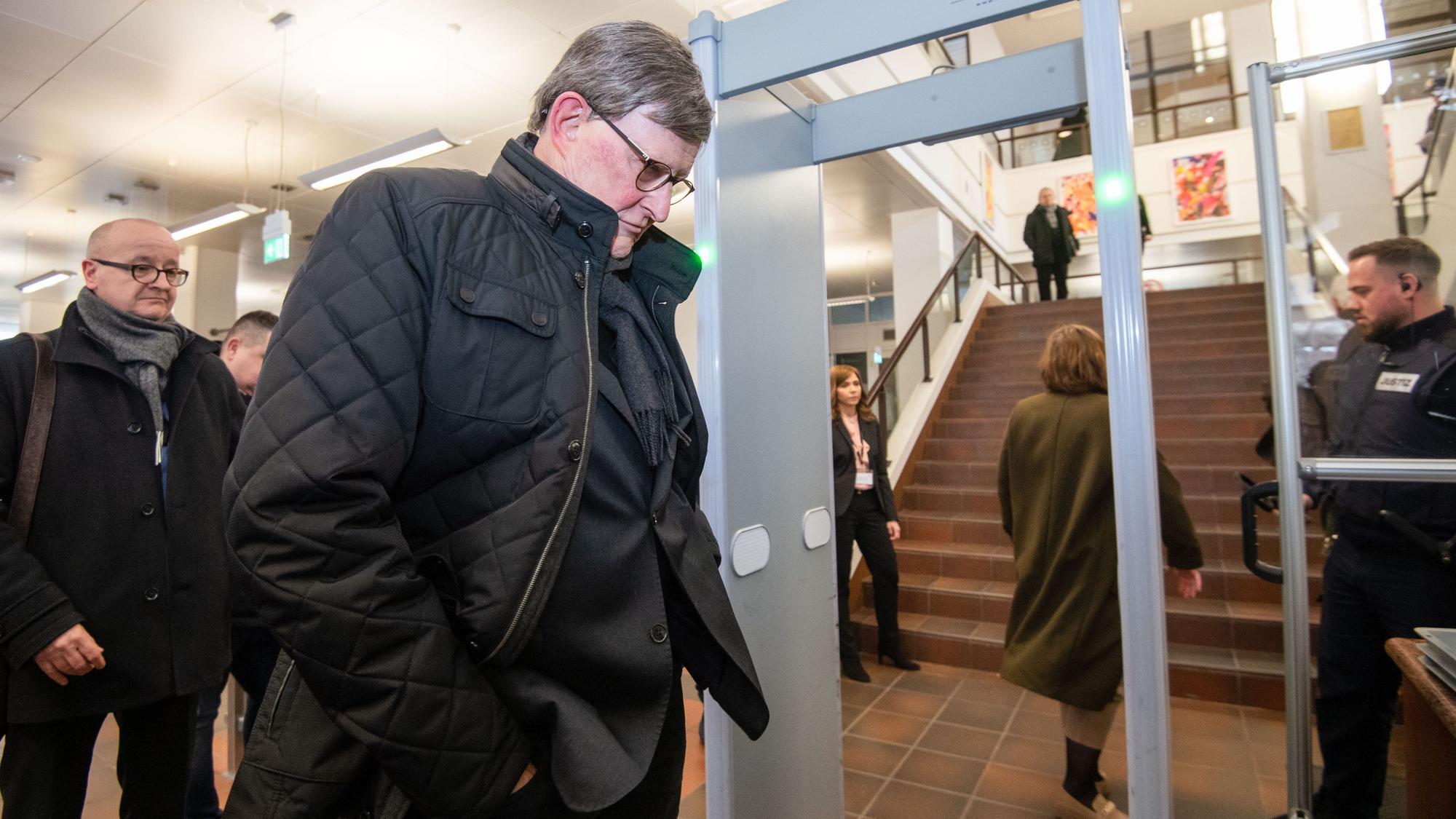 Kardinal Rainer Maria Woelki wartet im Foyer des Kölner Landgerichts vor der Sicherheitsschleuse.
