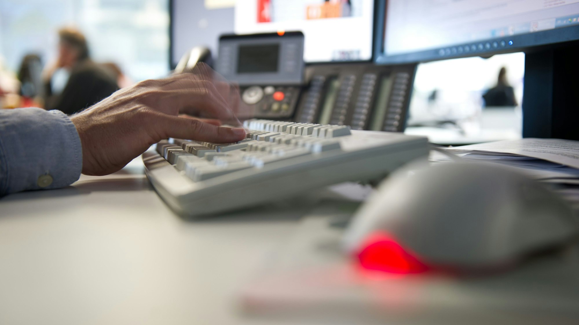 Ein Mann tippt einem Büro auf einer Tastatur (Langzeichtbelichtung).