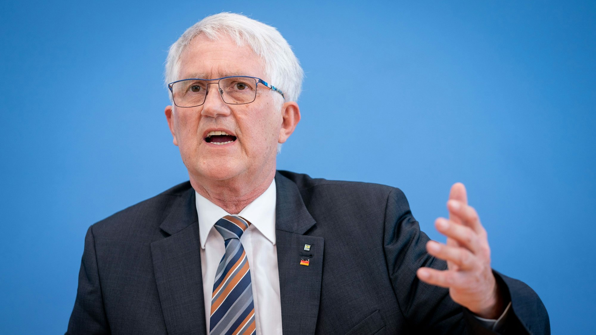 Georg Schirmbeck, Präsident des Deutschen Forstwirtschaftsrates, steht vor einer blauen Wand und gestikuliert.