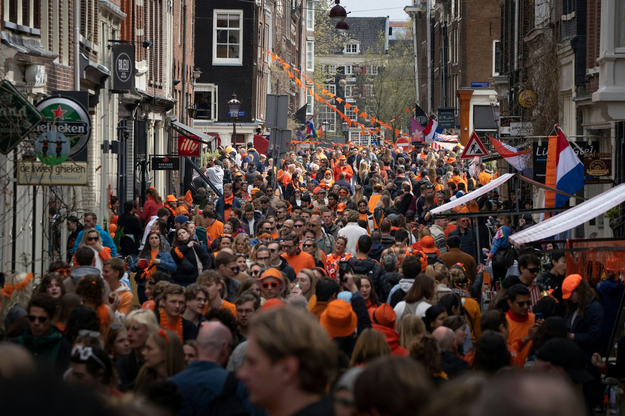 27.04.2023, Niederlande, Amsterdam: Orange gekleidete Menschen feiern den Königstag in einer Straße. Am 27.04.2023 feiert das Land den 56. Geburtstag von König Willem-Alexander.