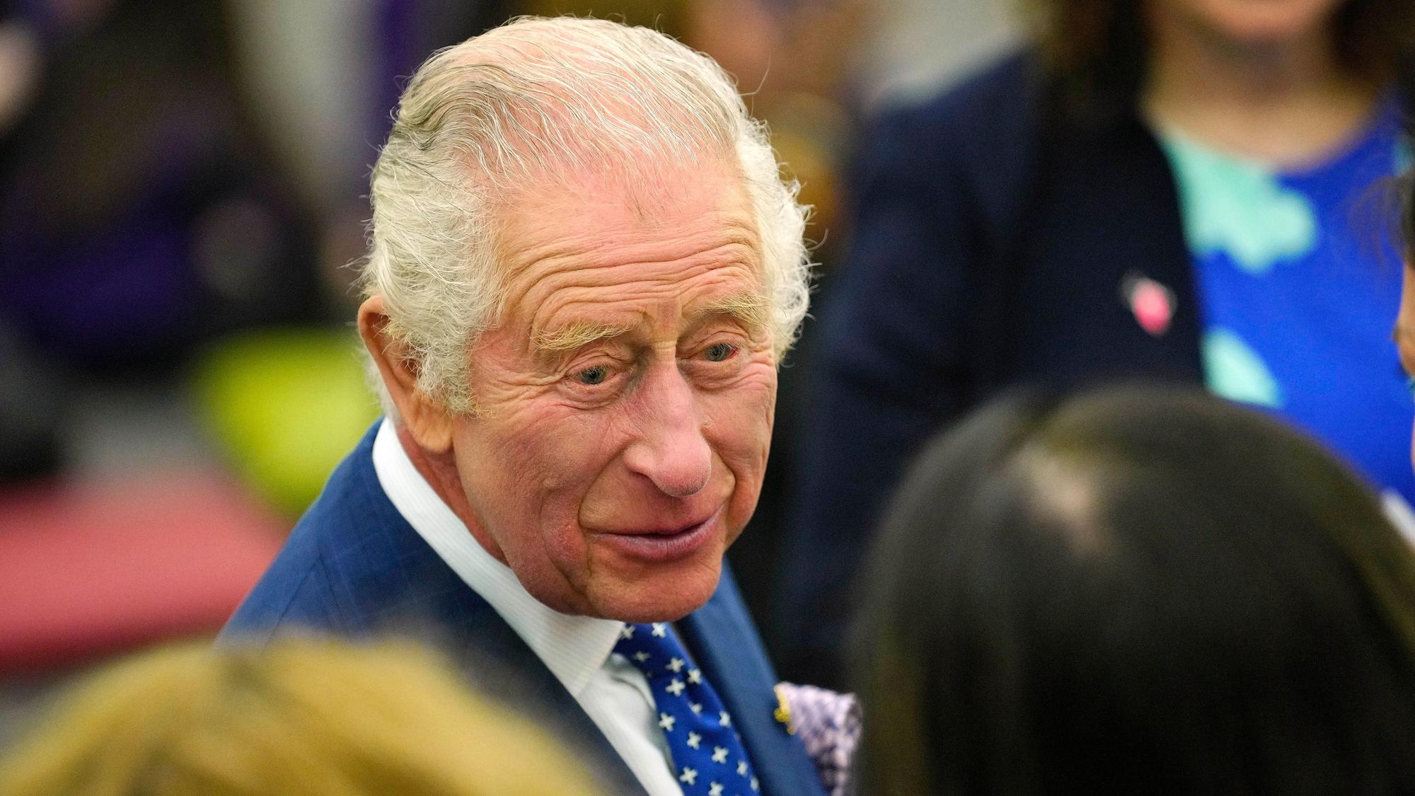 König Charles III. spricht bei einem Termin mit einer Frau. Zu seiner Krönung am 6. Mai sind auch neue „königliche“ Briefmarken von der Royal Mail erschienen.