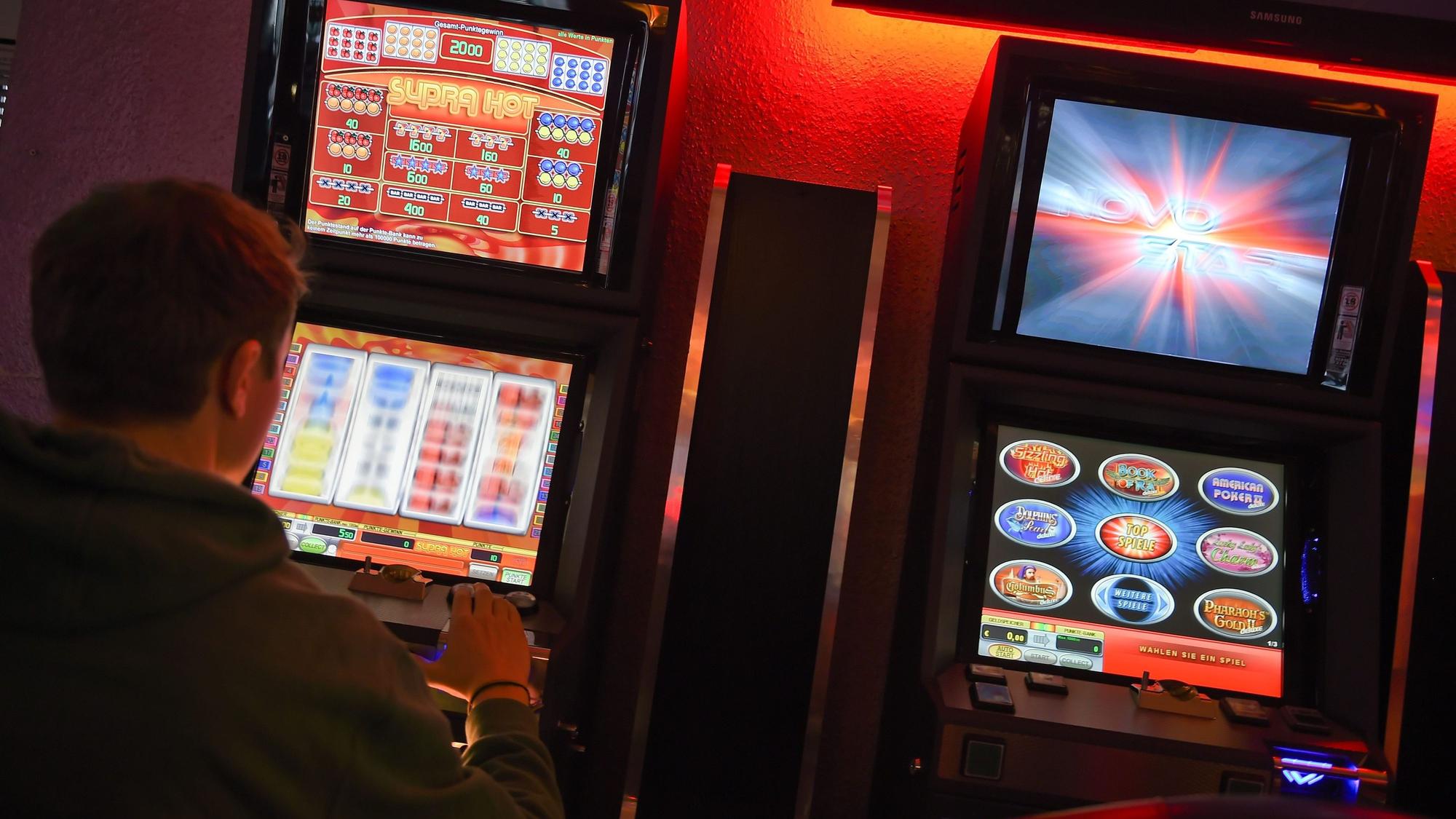 ARCHIV - 14.03.2015, Berlin: ILLUSTRATION - Ein junger Mann spielt an einem Spielautomaten.