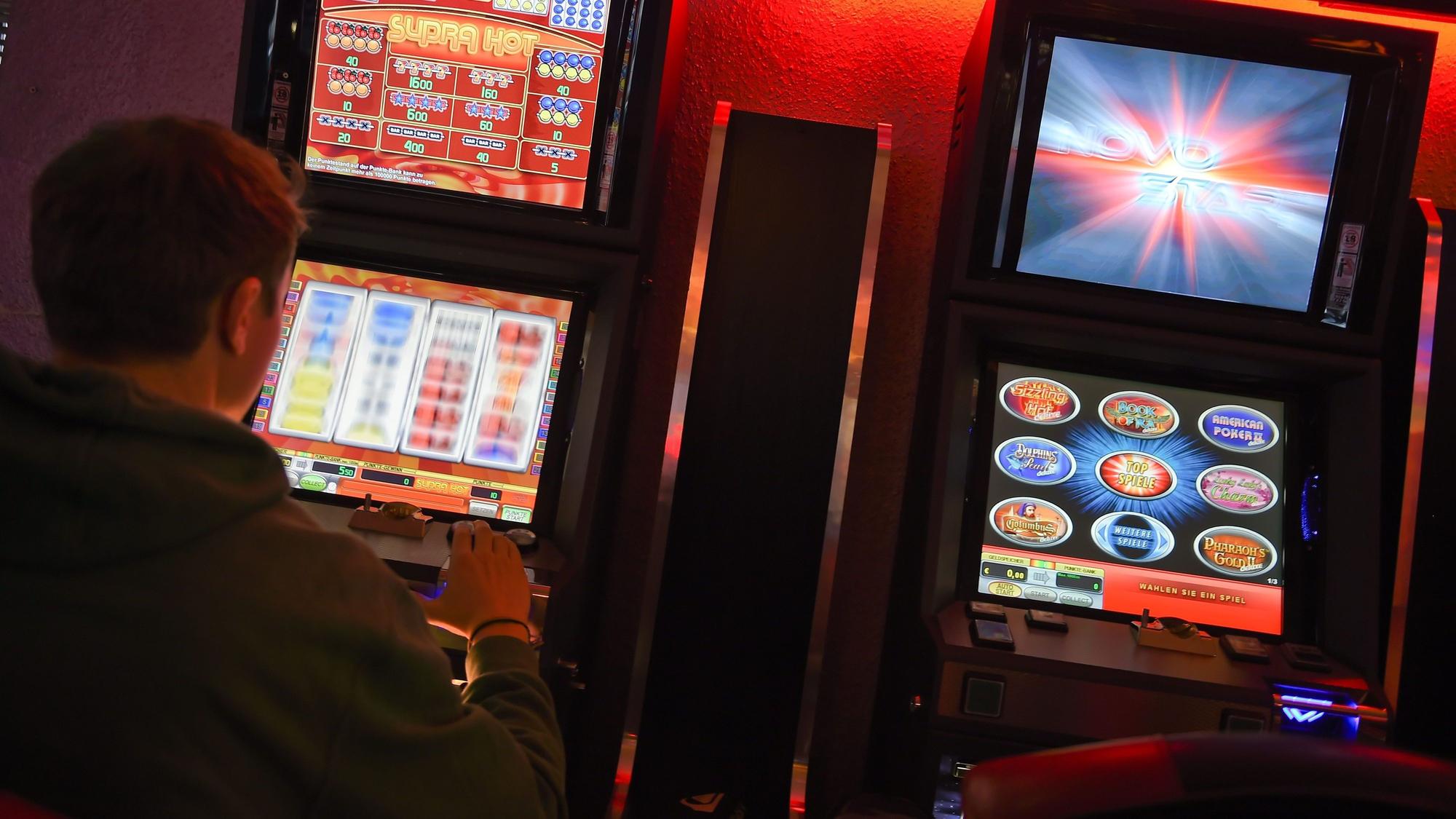 Ein junger Mann spielt an einem Spielautomaten.