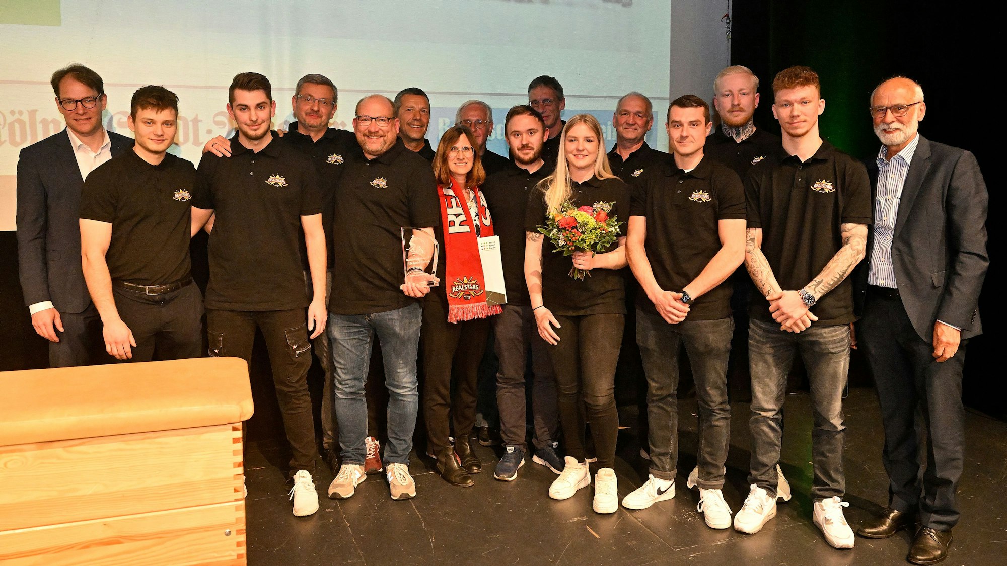 Eine Gruppe von Menschen steht auf der Bühne im Bürgerhaus Bergischer Löwe.