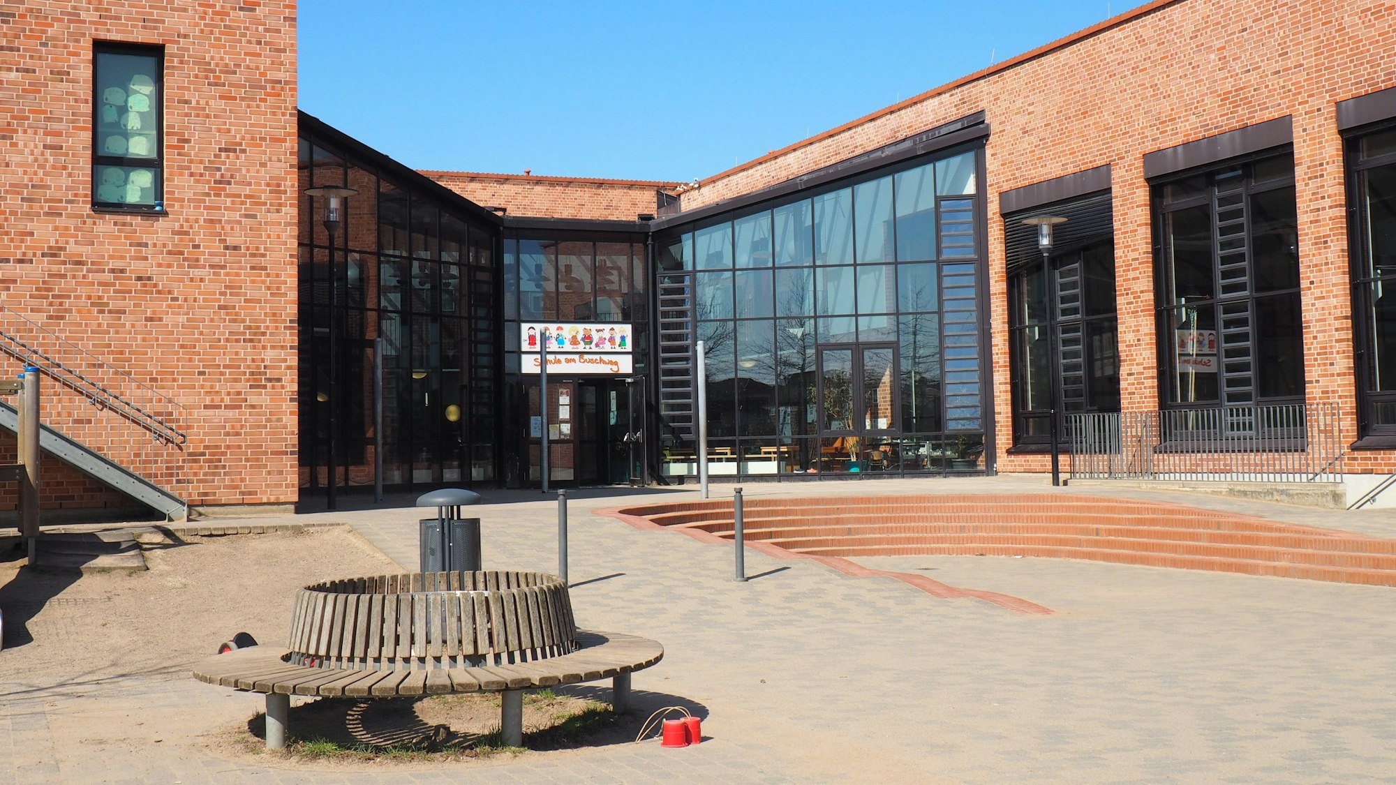 Blick auf den Eingang der Grundschule am Buschweg. Der Himmel ist strahlend blau.