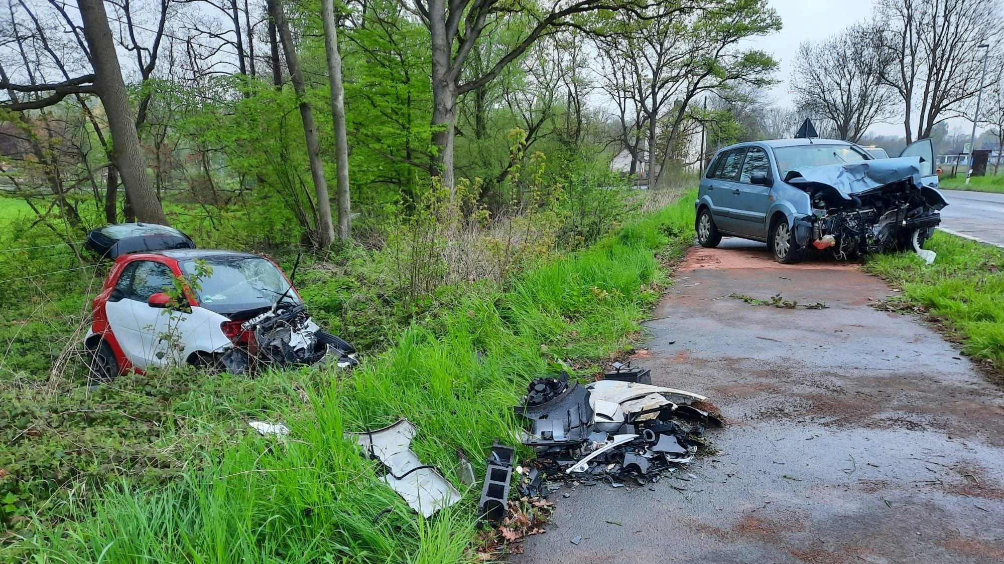 Zwei beschädigte Autos stehen nach einem Frontalzusammenstoß in Oberscheuren neben der Straße.