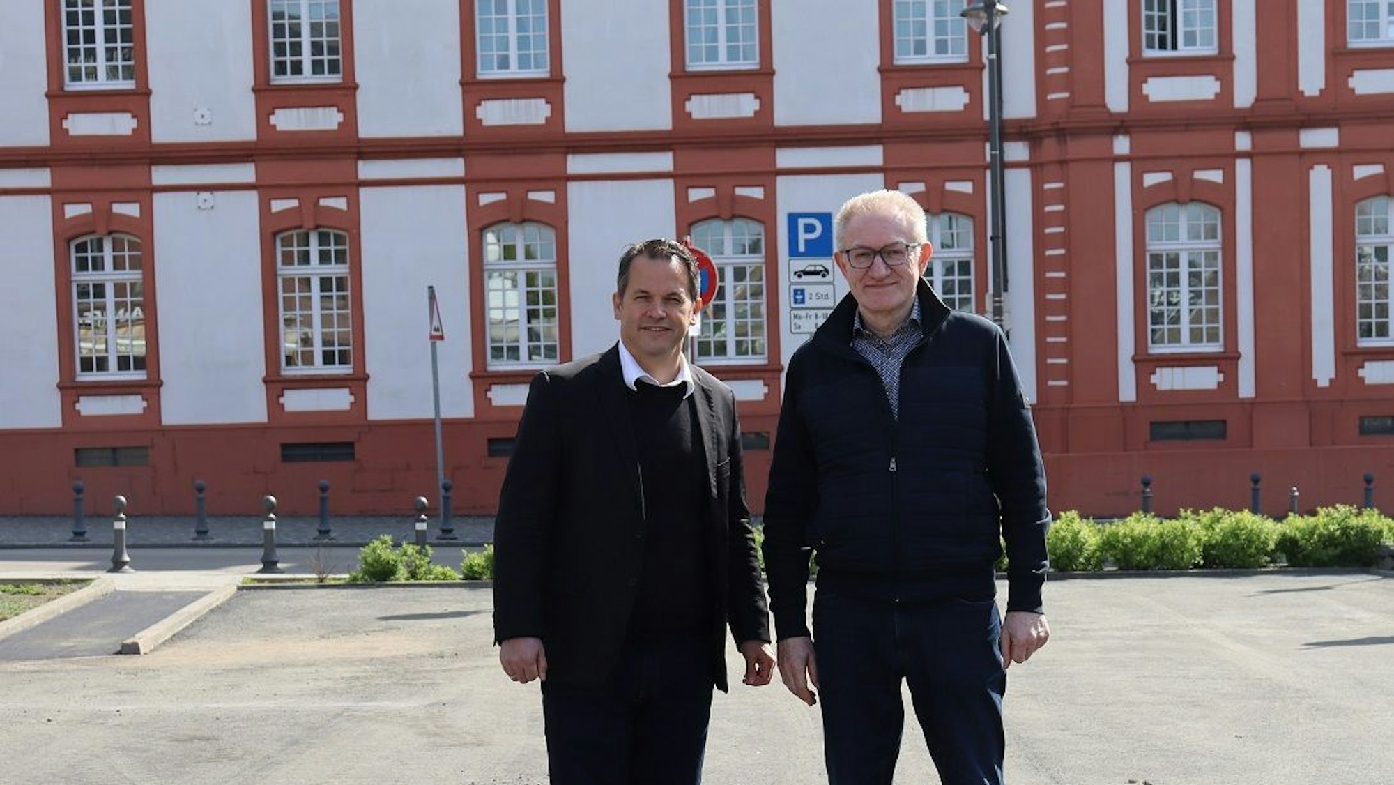 Die beiden Männer tragen dunkle Klamotten, stehen nebeneinander und blicken in die Kamera.