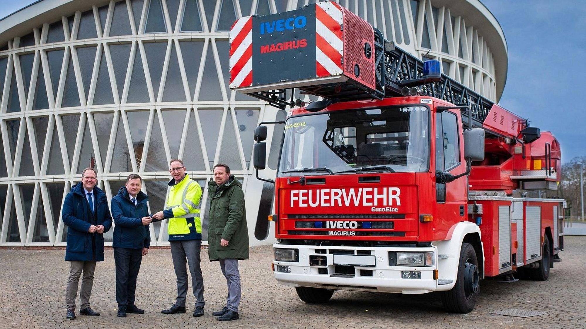 Die vier Männer stehen vor dem Feierabendhaus in Knapsack und neben ihnen steht der Drehleiterwagen.