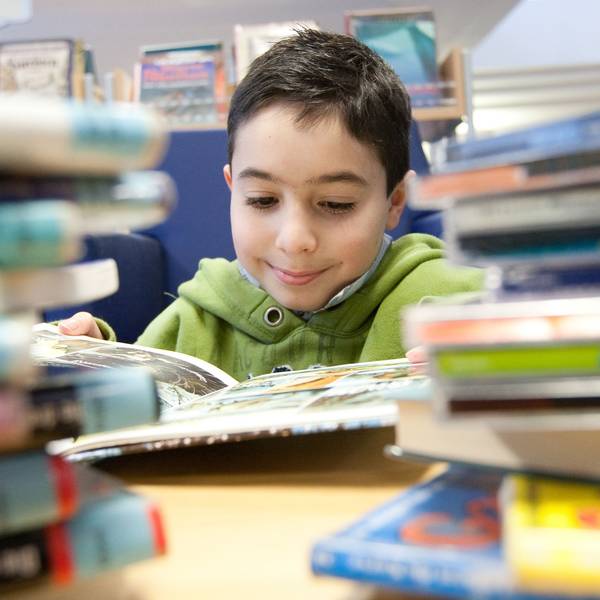 Ein Kind liest ein Buch in der Stadtbibliothek in Melle.