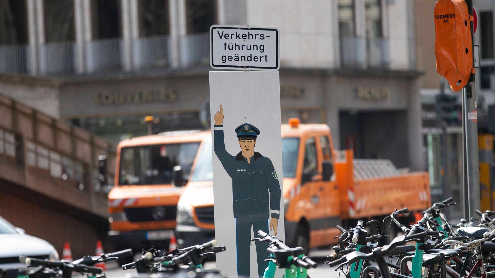 Ein Schild von einem Polizisten, der auf ein Schild mit der Aufschrift "Verkehrsführung geändert" zeigt.