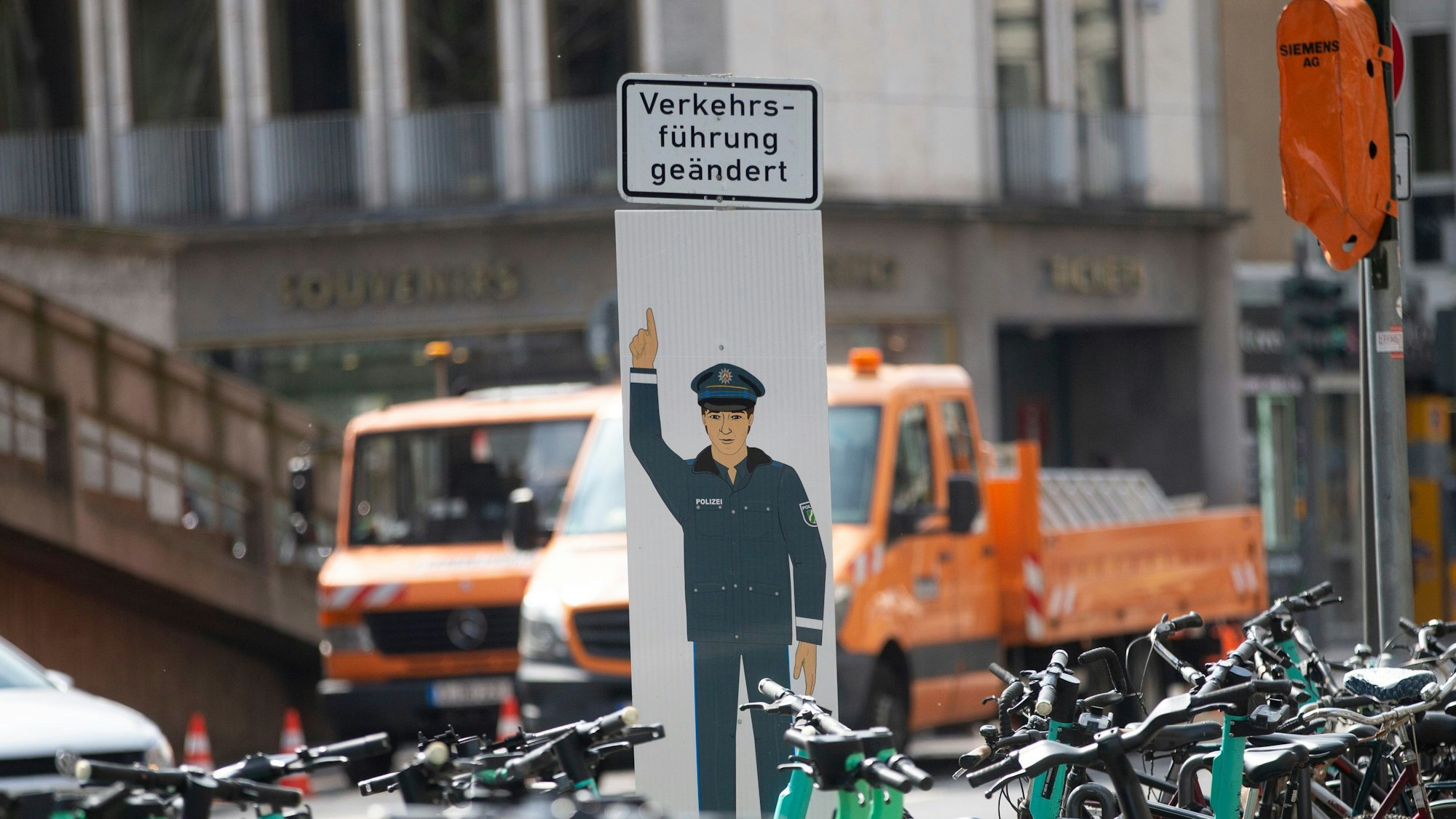 Ein Schild von einem Polizisten, der auf ein Schild mit der Aufschrift "Verkehrsführung geändert" zeigt.