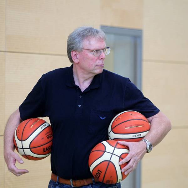Manager Frank Beier trägt drei Basketbälle unter den Armen.