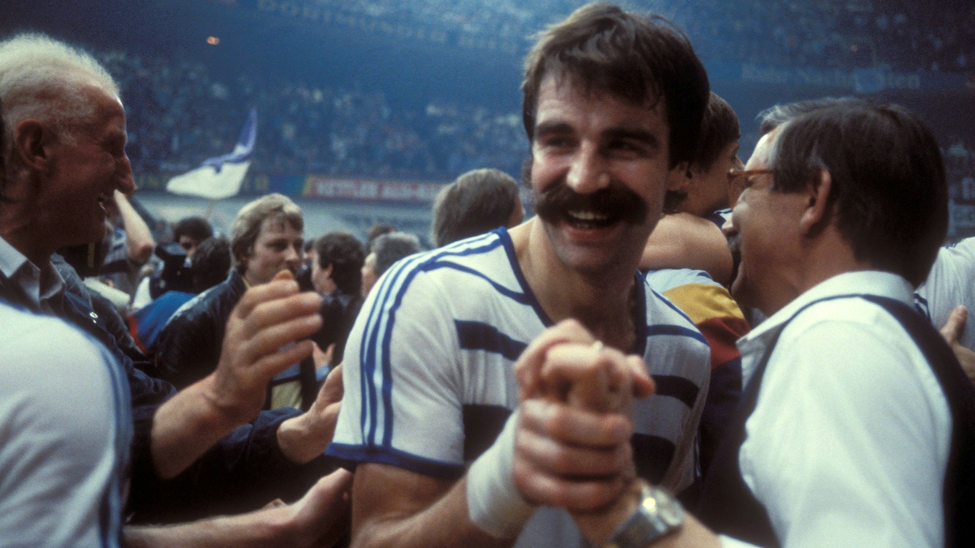 Im Bild ist ein Menschenauflauf zu sehen, die Personen freuen sich und gratulieren einander. Mittendrin ist Handball-Legende Heiner Brand.