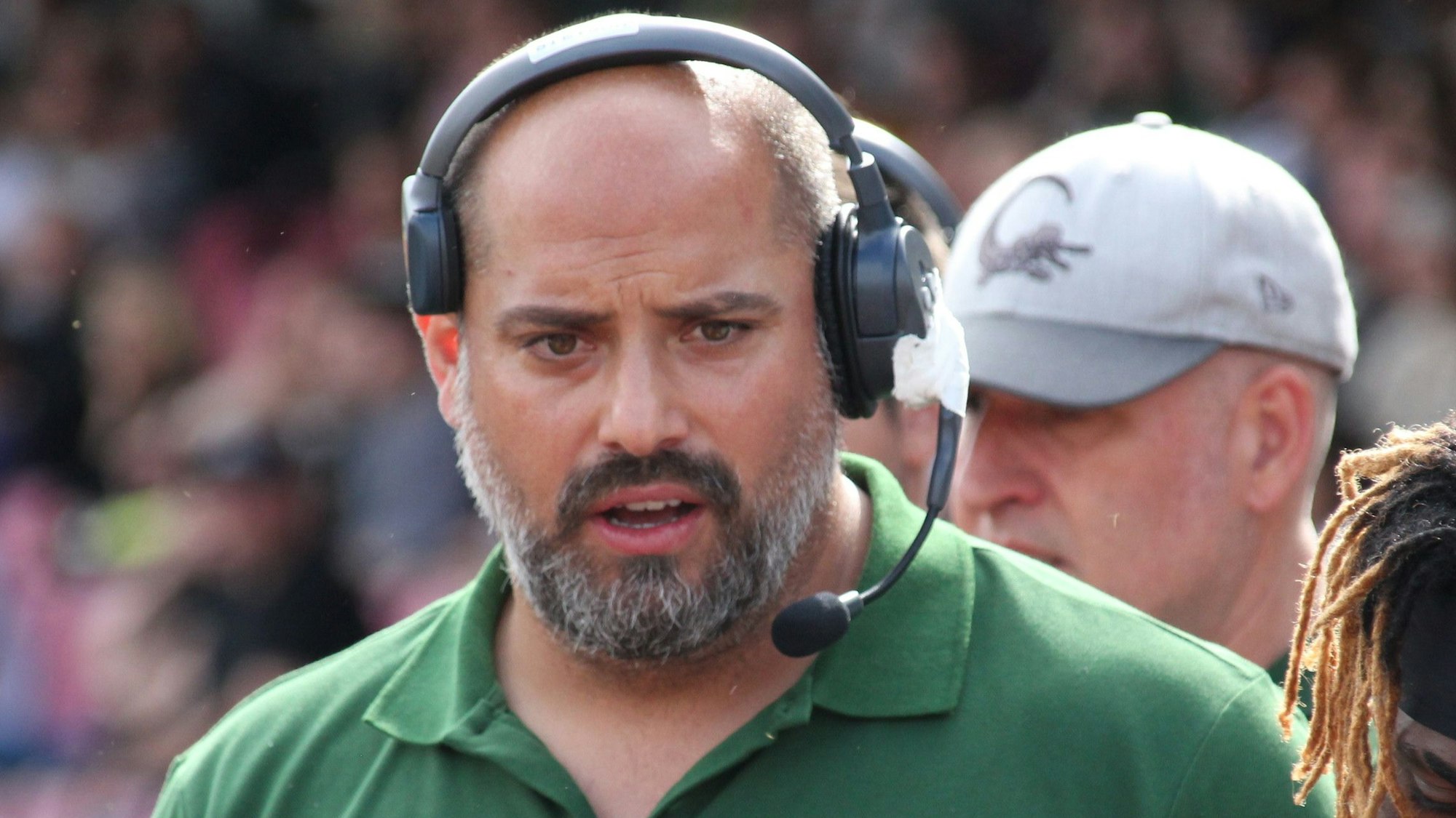 Ein Football-Trainer spricht Anweisungen in sein Headset.