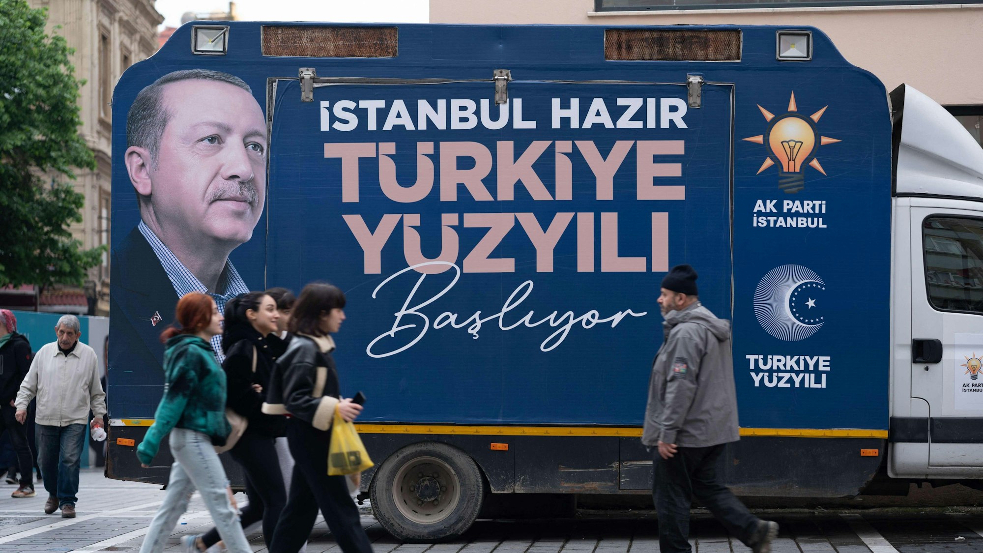 Passanten laufen an einem Lkw vorbei, auf dem ein Foto des türkischen Ministerpräsidenten Erdogan zu sehen ist.