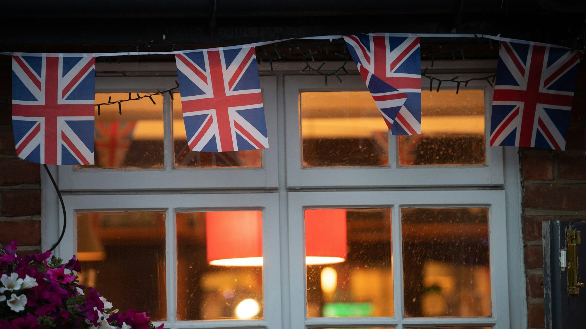 Union-Jack-Fahnen hängen am Fenster eines Pubs.