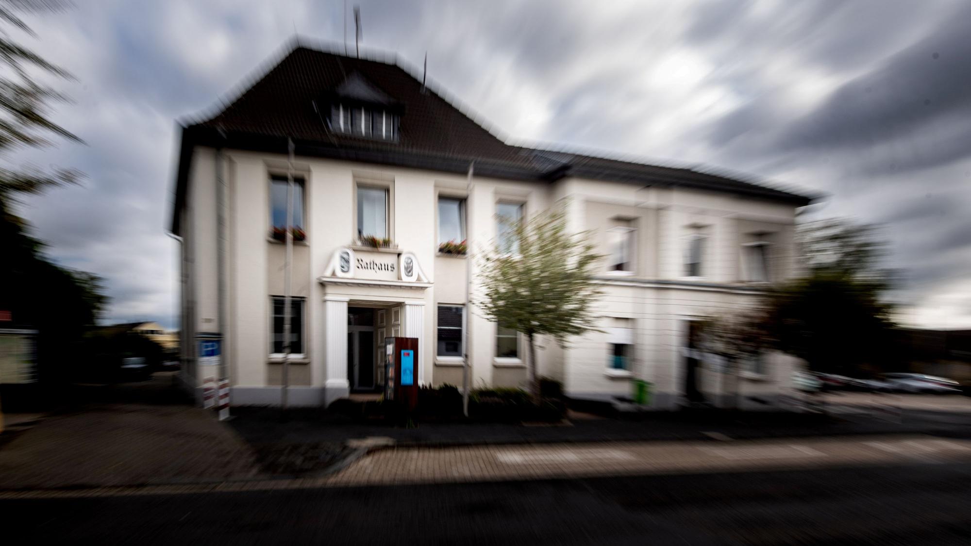Das Bild zeigt eine Außenansicht des Weilerswister Rathauses. Am Himmel sind dunkle Wolken zu sehen.