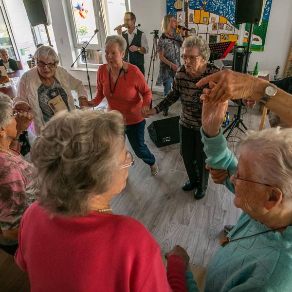 Senioren und Seniorinnen tanzen zu Schlagermusik in einem Partyraum.