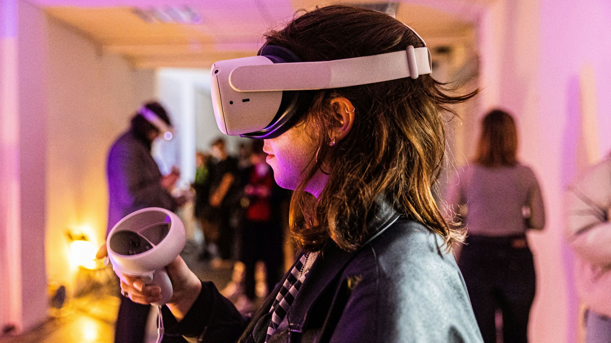 Eine junge Frau trägt eine VR-Brille und hält einen Joystick in der Hand.