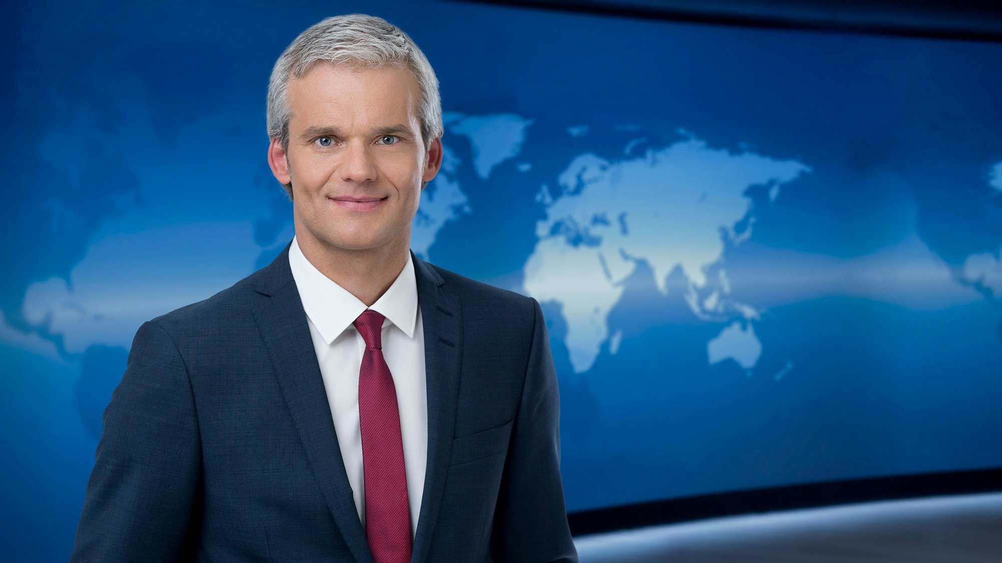 Thorsten Schröder, Sprecher der „Tagesschau“, steht vor einem blauen Hintergrund im Nachrichtenstudio in Hamburg.