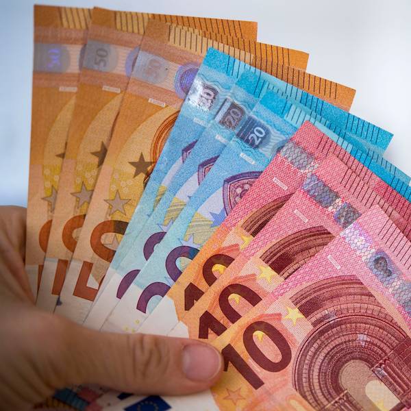 Eine Frau hält Banknoten von 10, 20 und 50 Euro gefächert in der Hand.