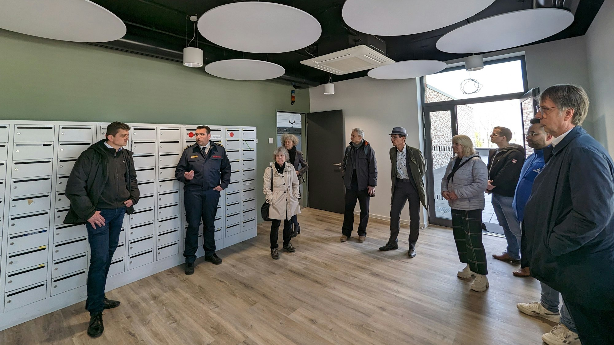 Es ist ein Raum der neuen Feuerwache zu sehen. In diesem stehen mehrere Menschen.