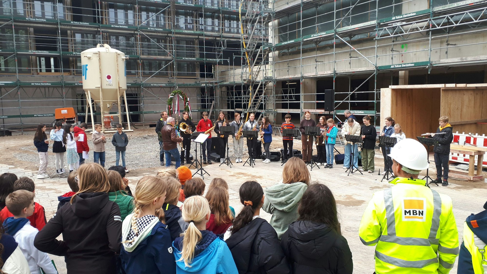 Schüler und Schülerinnen stehen vor dem Rohbau eines großen Gebäudes.