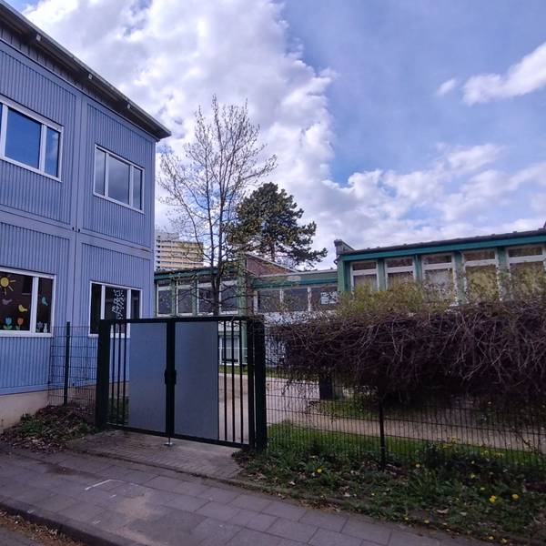 Ein blaues Container-Gebäude mit bunt beklebten Fenstern.