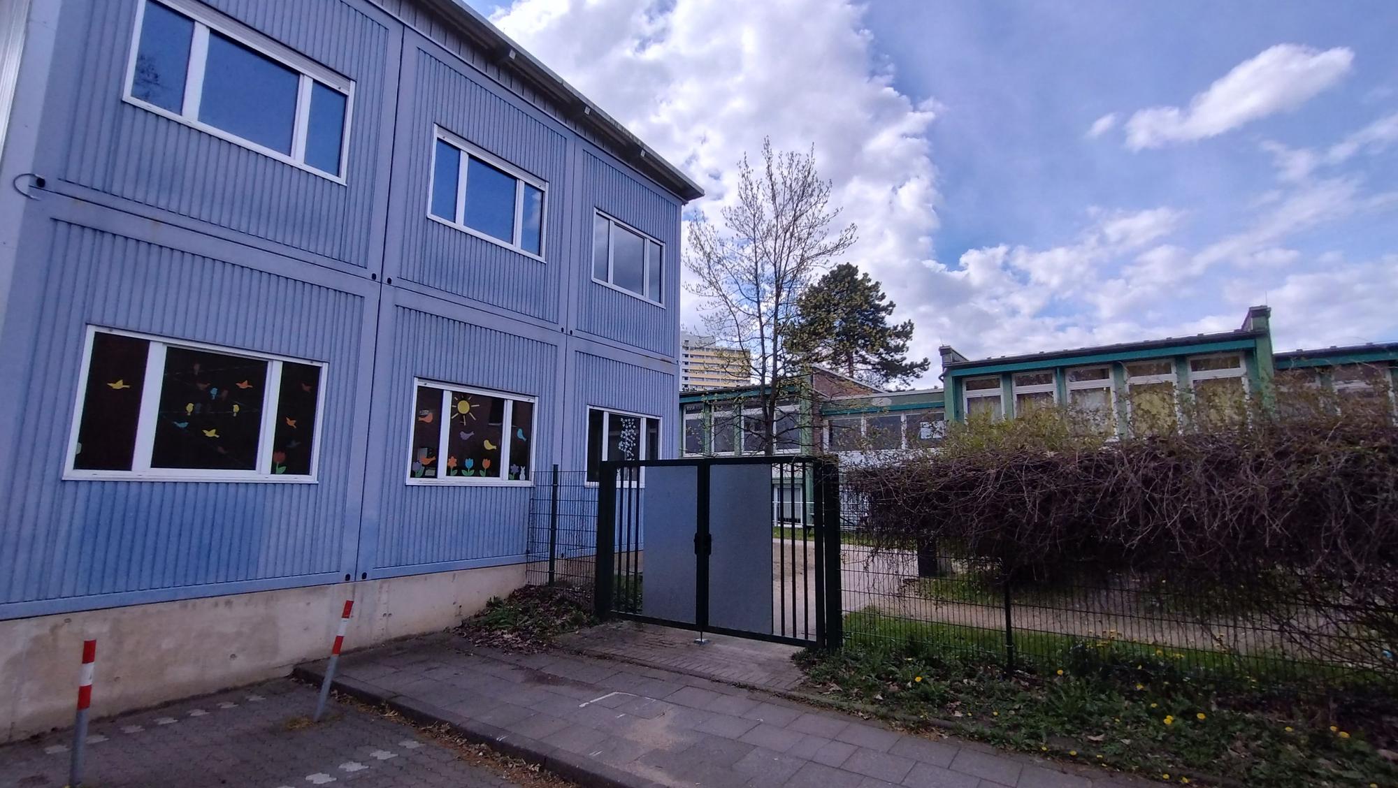 Ein blaues Container-Gebäude mit bunt beklebten Fenstern.