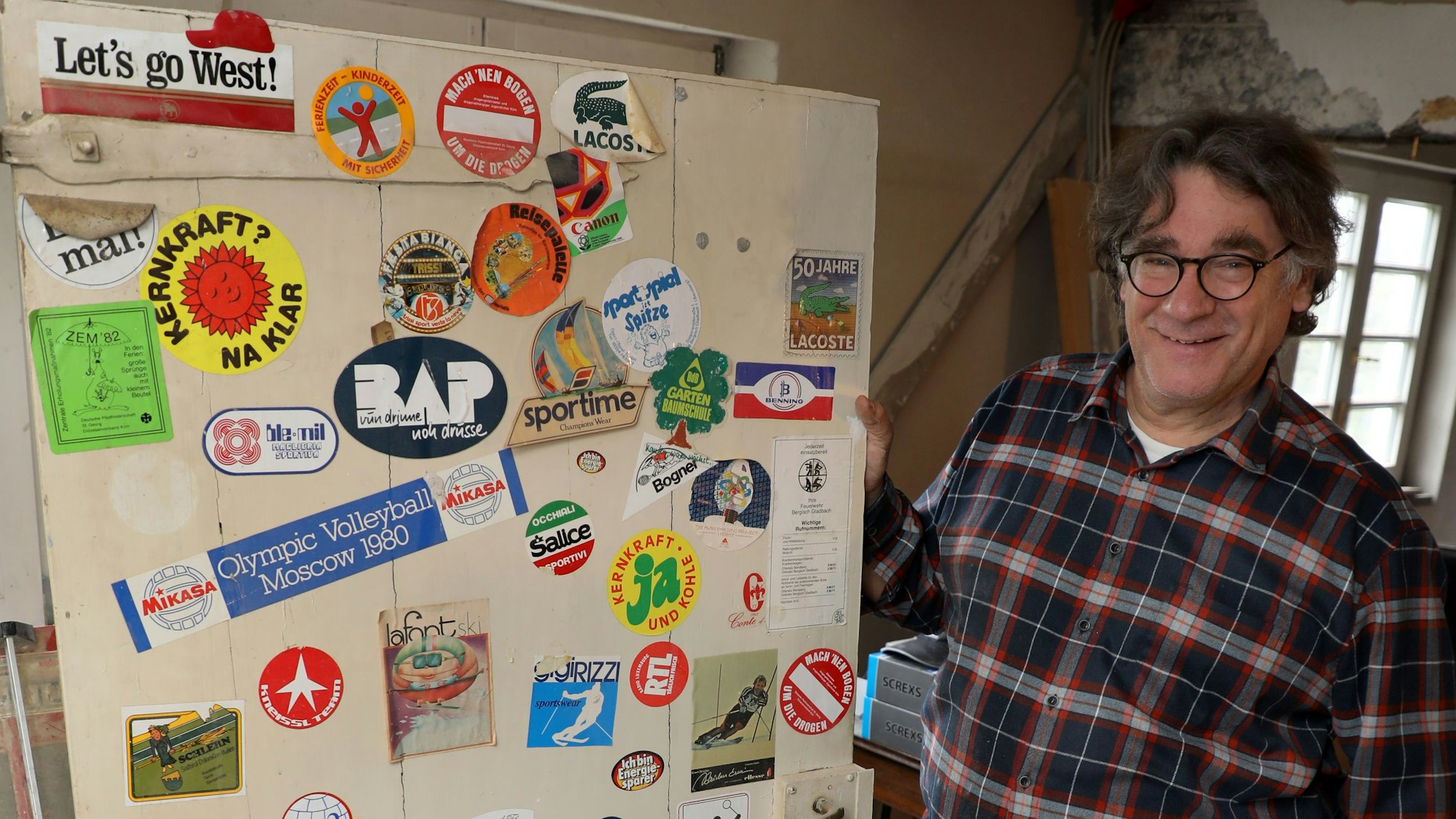 Es ist Friedrich Bock mit seiner bunt mit Stickern beklebten Jugendzimmertür zu sehen.