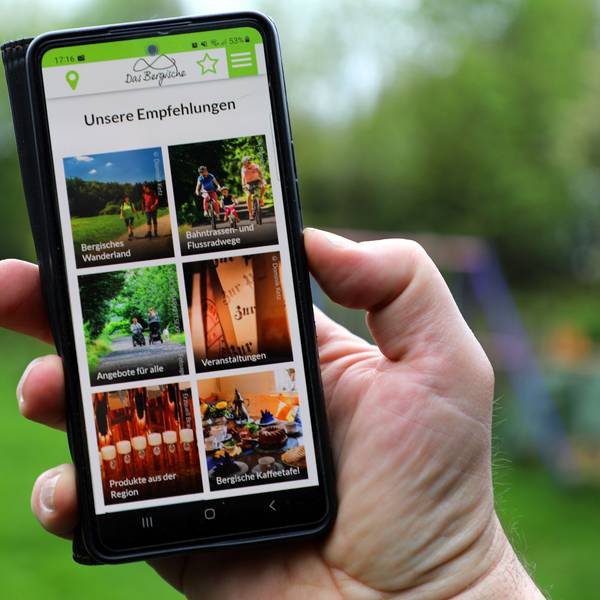 Die Freizeit-App von „Das Bergische“ wird auf einem Smartphone in einer Menschenhand dargestellt.