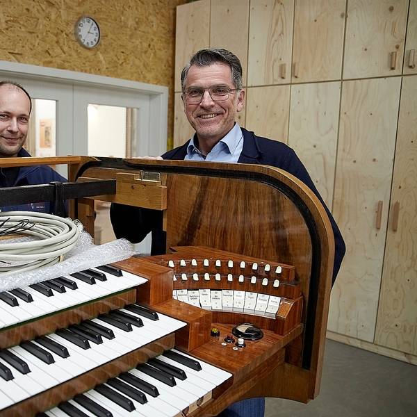 Zwei Männer stehen an einer historischen Orgel, in die nun digitale Technik eingebaut wird.