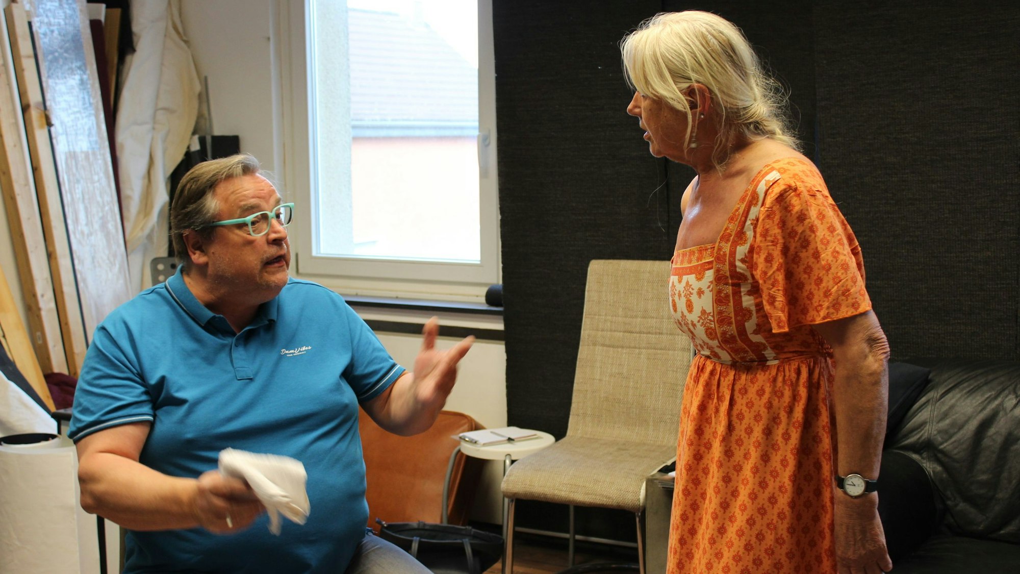 Ein Mann gestikuliert im vermeintlichen Streit mit seiner Ehefrau auf einer Theaterbühne.