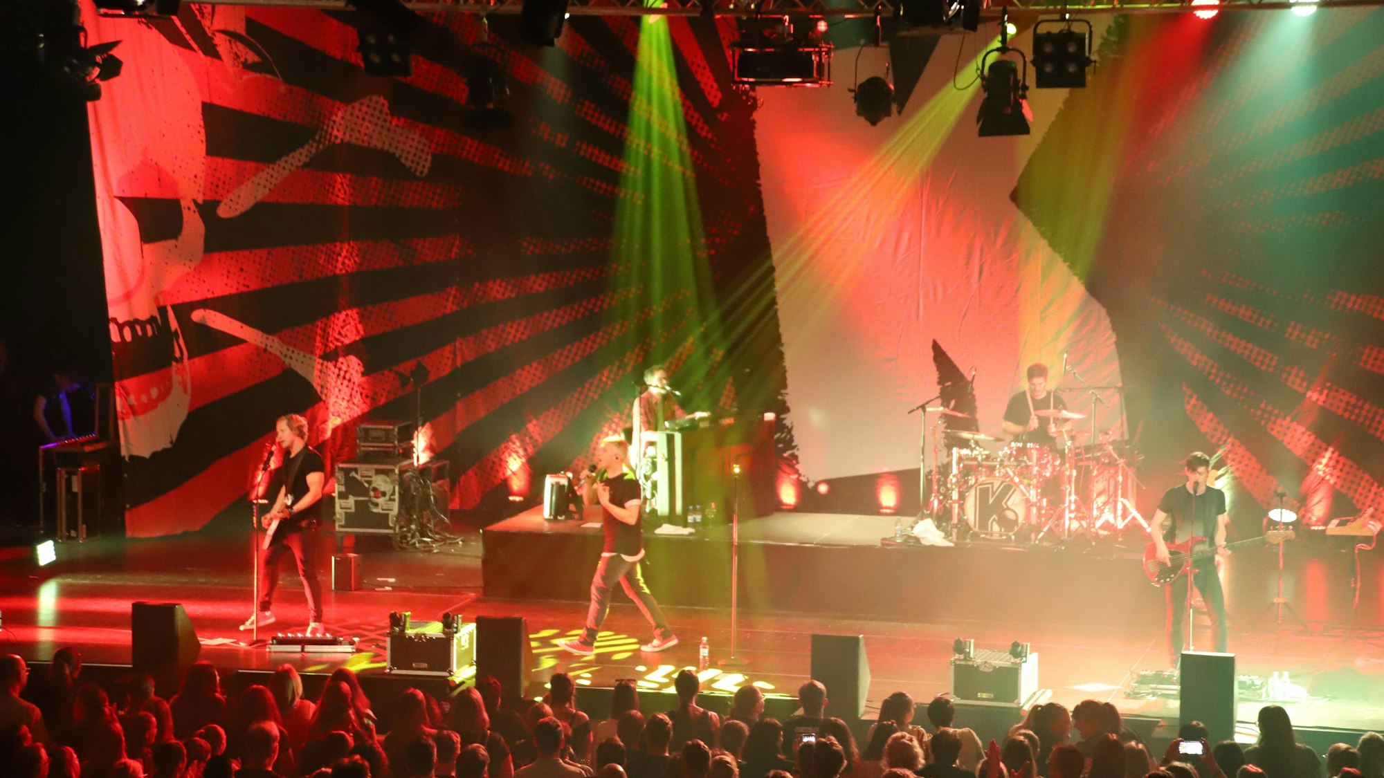 Die kölsche Kultband Kasalla spielt vor Publikum auf einer angeleuchteten Bühne.