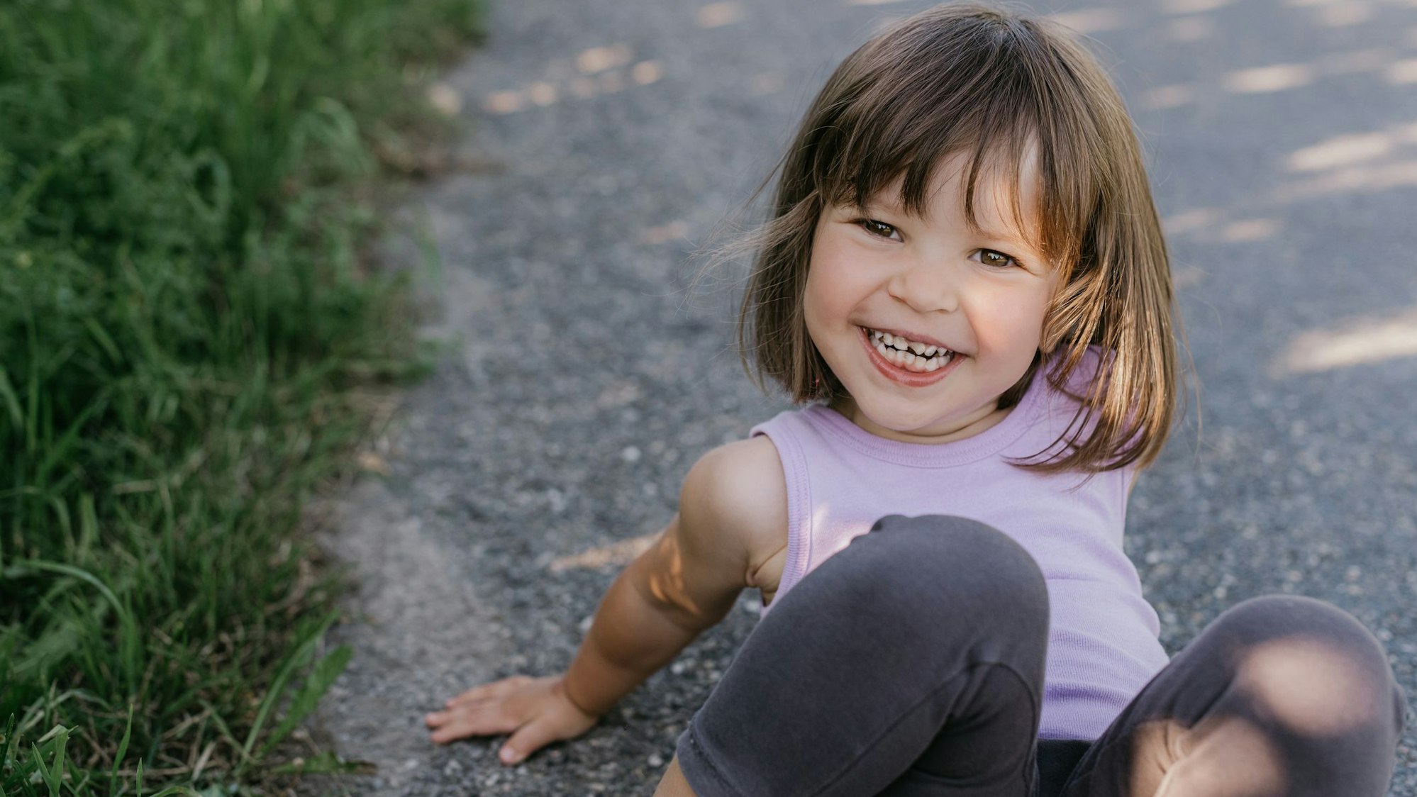 Ein kleines Mädchen sitzt auf dem Boden und lacht.