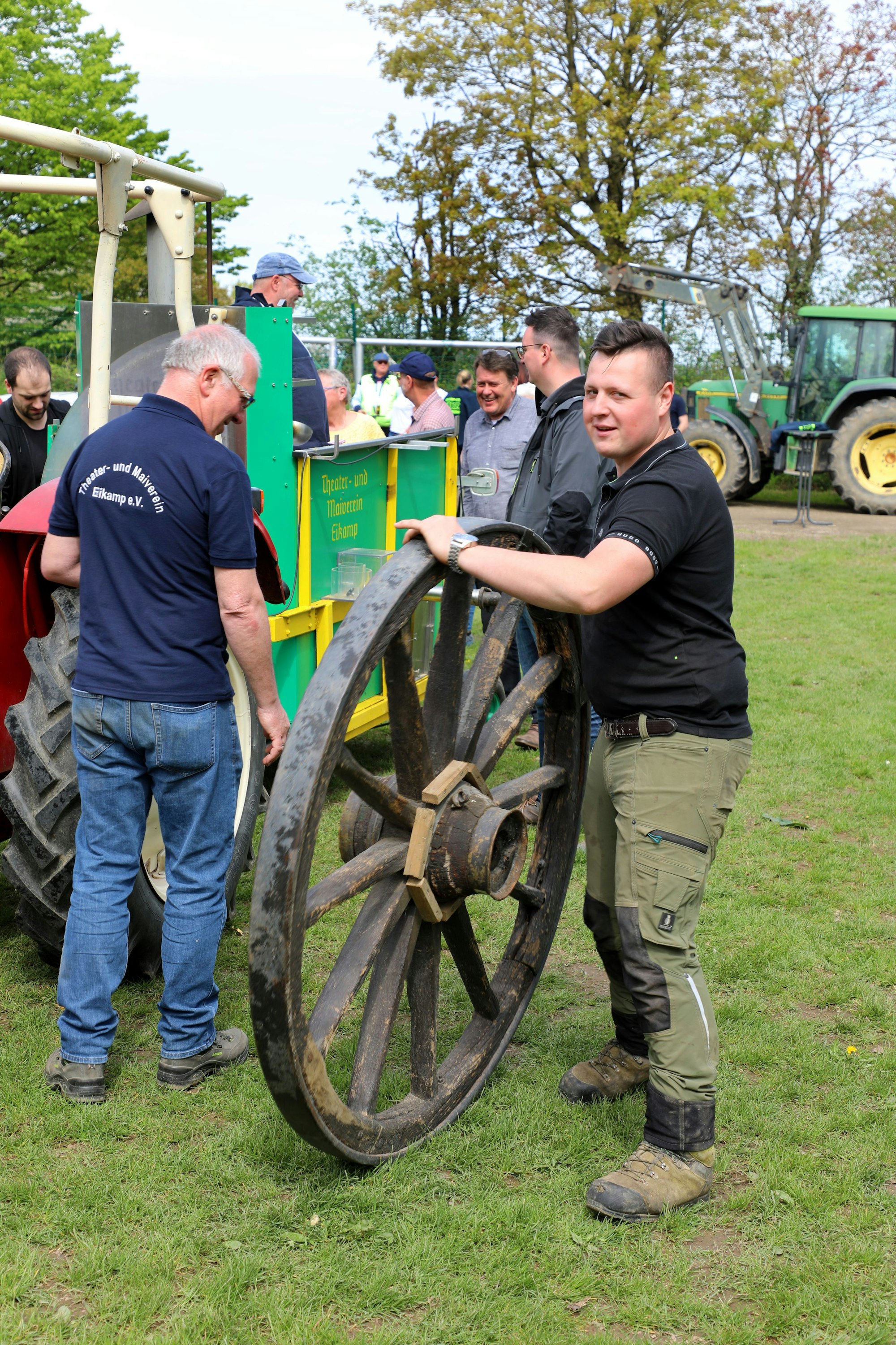 Ein Mann hält ein großes, hölzernes Schauwagenrad.