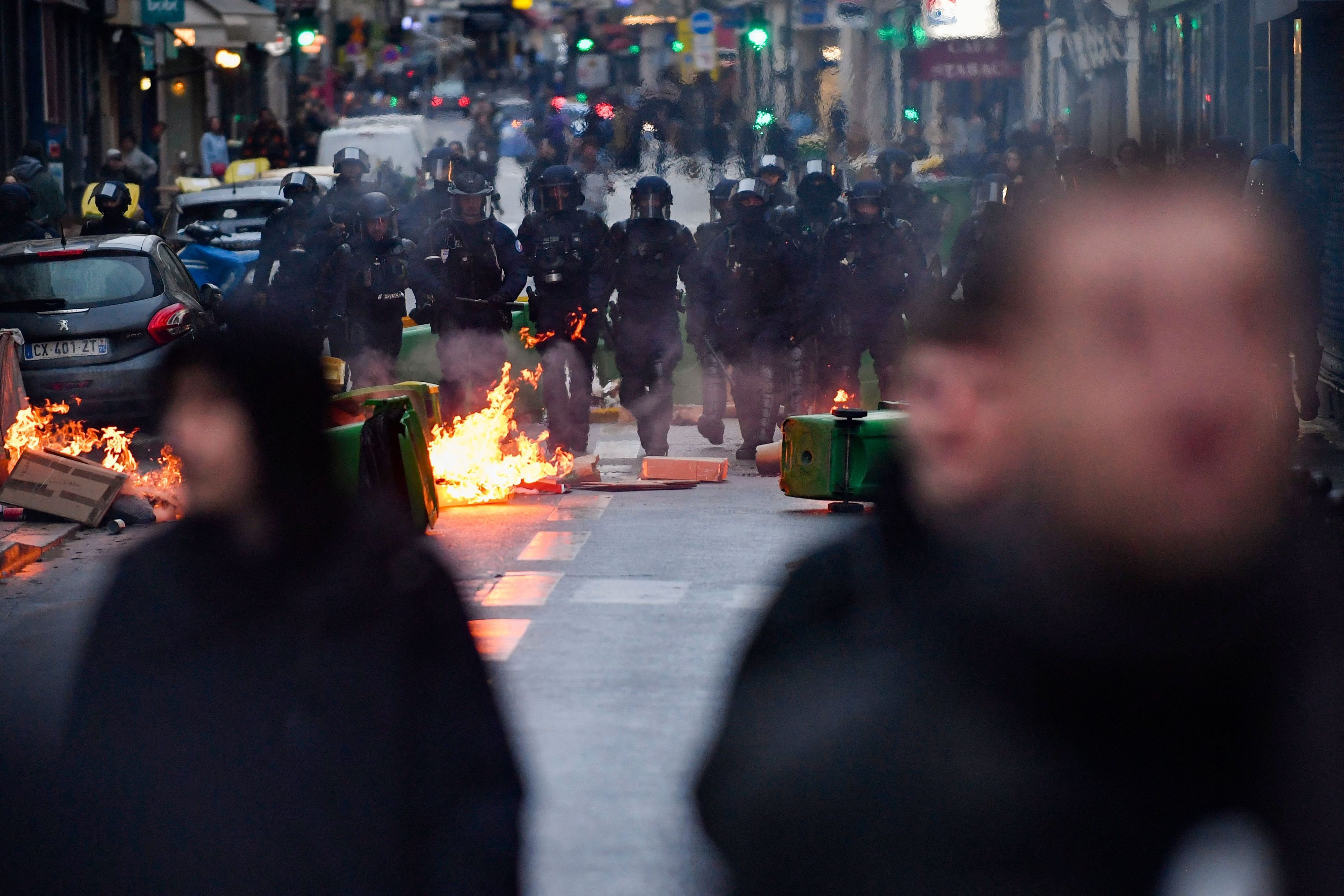 14.04.2023, Frankreich, Paris: Polizisten gehen während einer Demonstration an einem Feuer vorbei, nachdem das französische Verfassungsgericht die wichtigsten Elemente der umstrittenen Rentenreform gebilligt hat.